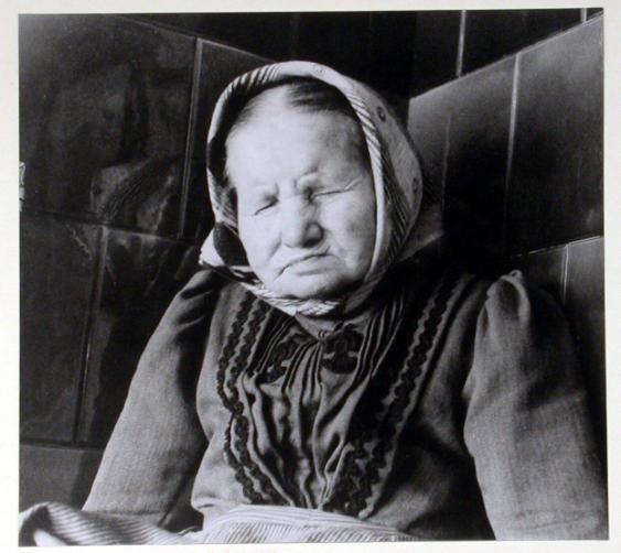Porträt alte Frau mit Kopftuch auf dem Kachelofen